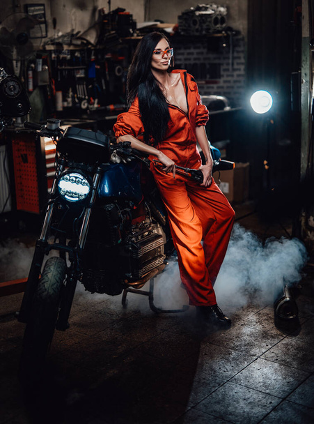 Krásná bruneta opírající se o černý motocykl - Fotografie, Obrázek