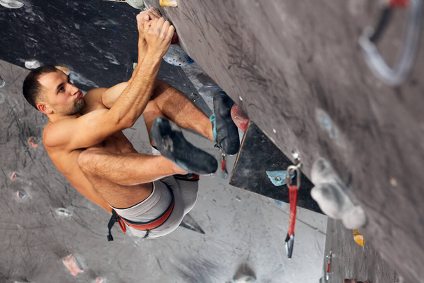 Male professional climber at indoor workout at bouldering centre. - Foto, imagen