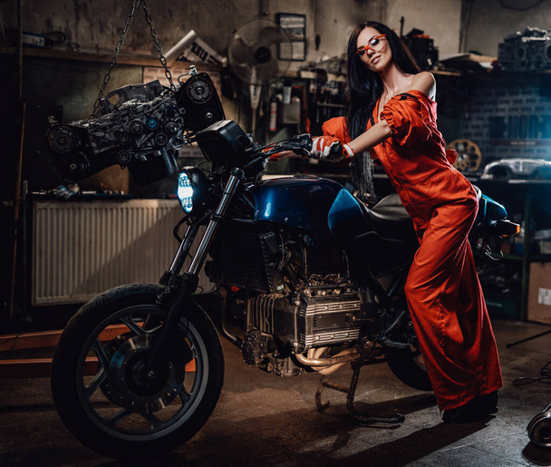 Fiatal szexi nő támaszkodik a fekete motorkerékpár - Fotó, kép
