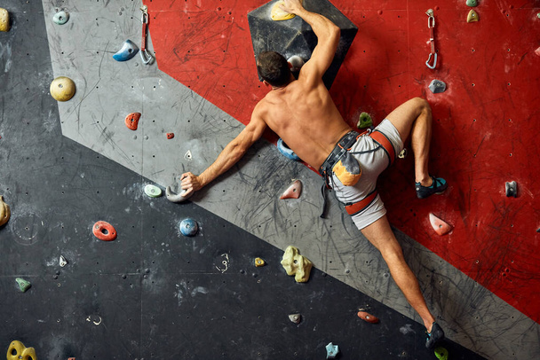 Male professional climber at indoor workout at bouldering centre. - Fotó, kép