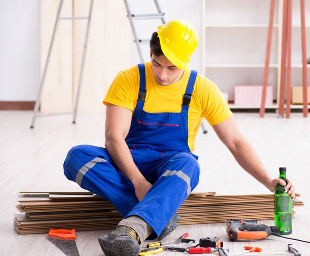 Floor repairman drinking alcohol during break - Foto, imagen