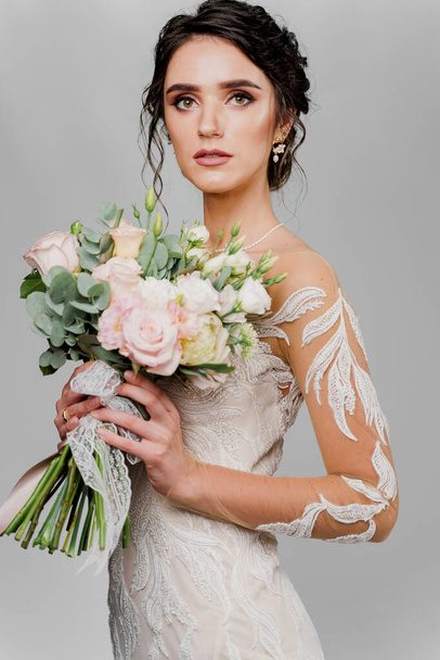 結婚式の花束の花嫁はカメラで見る。ソーシャルネットワークのための魅力的な女の子の縦の肖像画。女の子で結婚式のガウン上の空白の背景 - 写真・画像