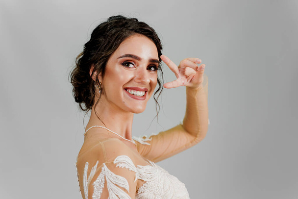 Bride having fun and shows peace sign hands and smiles. Girl in wedding dress - Foto, immagini
