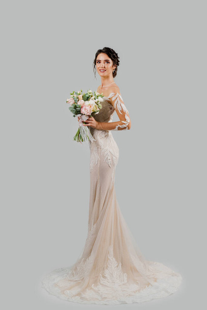 Girl in wedding dress on white blank background. Bride in white wedding dress with bouquet in studio - Photo, image