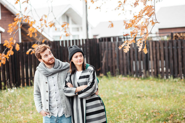 Happy young couple sitting outdoor, in front of their new home in autumn day - Foto, imagen