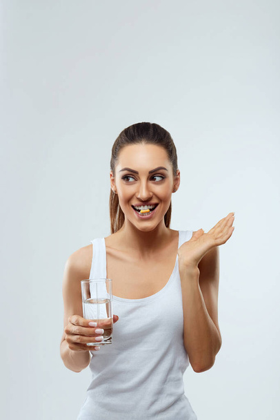 Beautiful Woman Opened Mouth Holding Vitamin Pill In White Teeth. Smiling Girl Holding Capsule With Omega-3 Between Teeth. Healthy Diet Nutrition Concept - Foto, Imagen