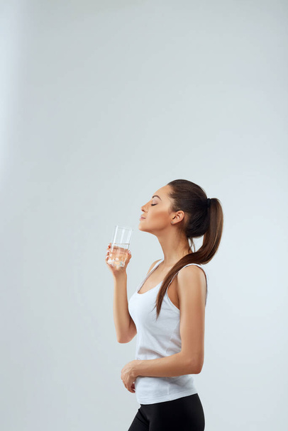 美顔の美しい女性の肖像画は、水のガラスを保持します。水を飲む。水のガラスの女の子。国会の概念 - 写真・画像