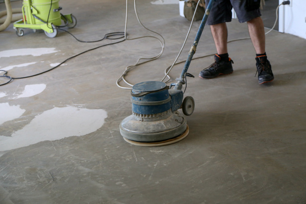 Pracovník mlející podlahu pomocí jednoho kotoučového stroje - Fotografie, Obrázek