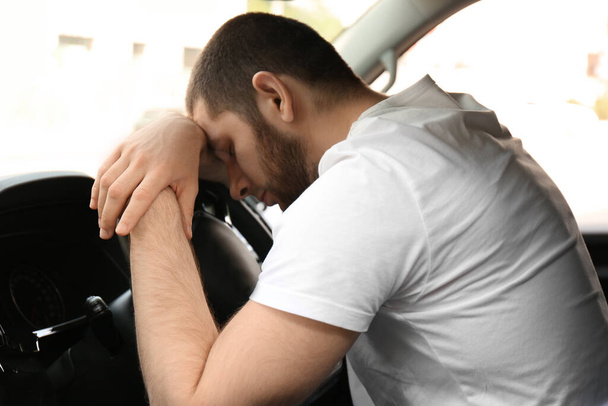 Tired man sleeping on steering wheel in his car - Foto, immagini