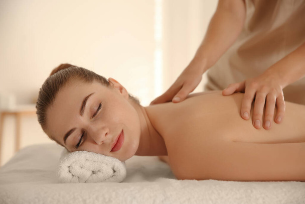Giovane donna riceve massaggio alla schiena nel salone spa - Foto, immagini