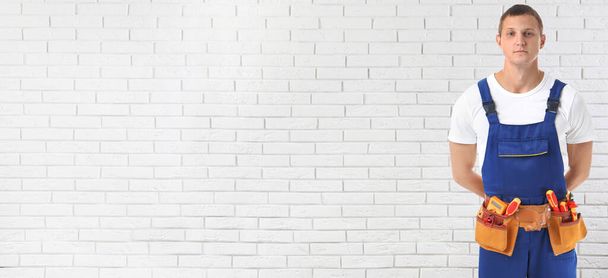 Electrician with tools near white brick wall, space for text. Banner design - Фото, изображение