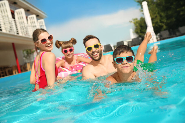 Happy family in swimming pool on sunny day - Foto, Bild