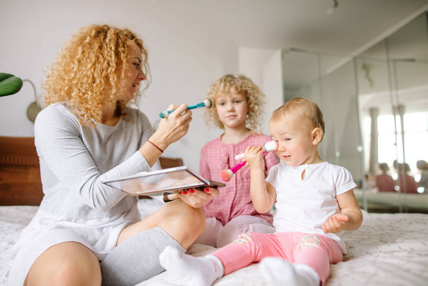 happy ginger mother and her little children playing with brushes - 写真・画像