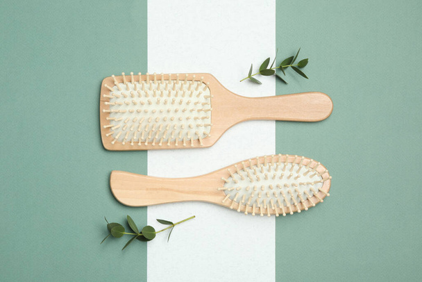 Wooden hair brushes and green twigs on color background, flat lay - Foto, Bild