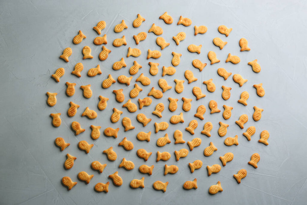 Delicious goldfish crackers on grey table, flat lay - Φωτογραφία, εικόνα