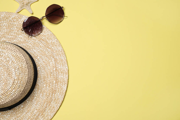 Hat, sunglasses and starfish on yellow background, flat lay with space for text. Beach objects - Zdjęcie, obraz