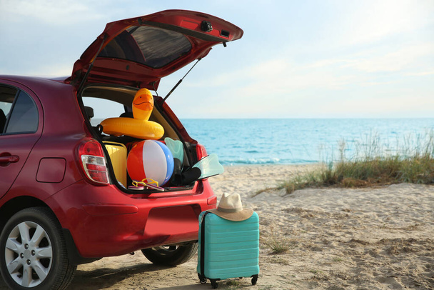 Red car luggage on beach, space for text. Summer vacation trip - Φωτογραφία, εικόνα