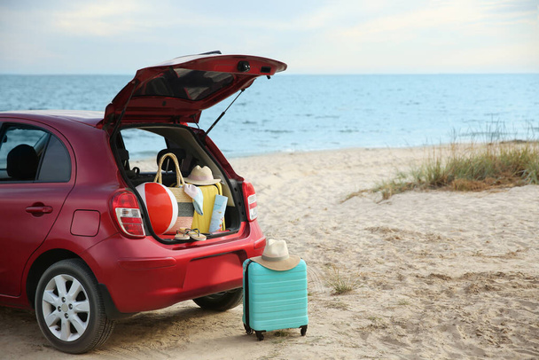 Red car luggage on beach, space for text. Summer vacation trip - Фото, изображение