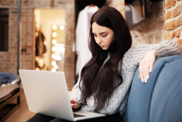 Kobieta w ubraniu casual za pomocą laptopa i uśmiecha się podczas pracy w pomieszczeniach - Zdjęcie, obraz