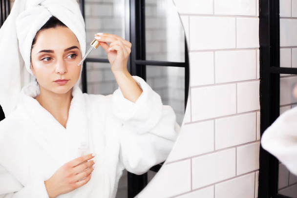 Junge Frau nach der Dusche wird Hautpflegeprodukt, Öl oder Serum anwenden. - Foto, Bild