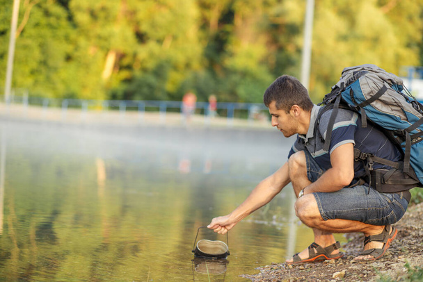 holidaymaker is sitting with bucket on the bank of the river - Photo, image