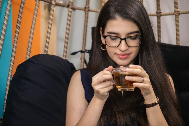 Gyönyörű nő szemüveggel ül és teát iszik délutánonként. üzletasszony iszik teát pihentető idő alatt a munka. - Fotó, kép