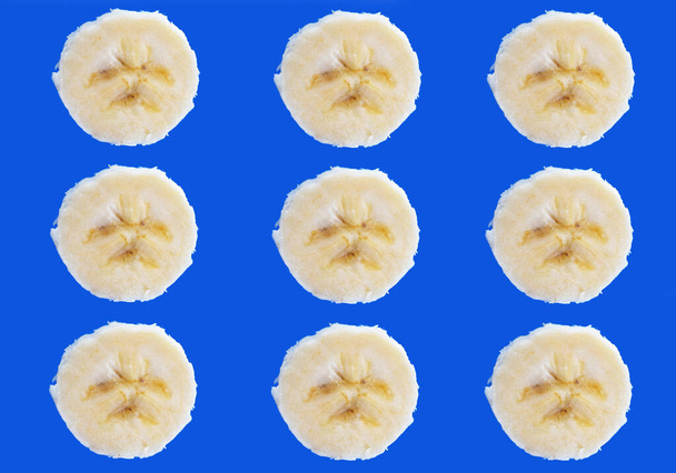 Pezzi di banana a fette su uno sfondo blu brillante. - Foto, immagini