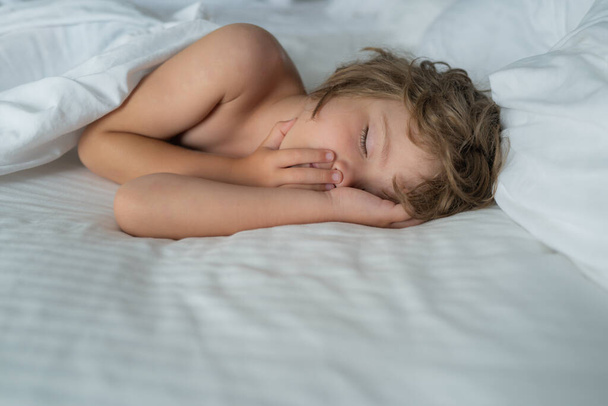 Healthy kids boy, sweetest blonde toddler kids sleeping in bed. Bedding linen and mattress in bedroom. - Photo, image