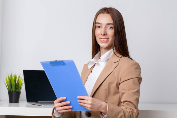 Happy beautiful business woman with clipboard in the office. - Fotografie, Obrázek