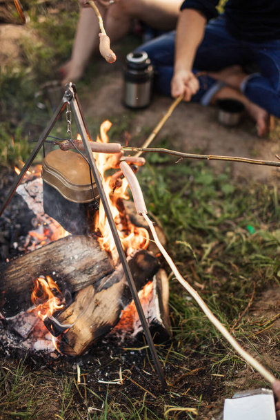 close up cropped photo. tourists are roasting sausages on the campfire - Fotografie, Obrázek