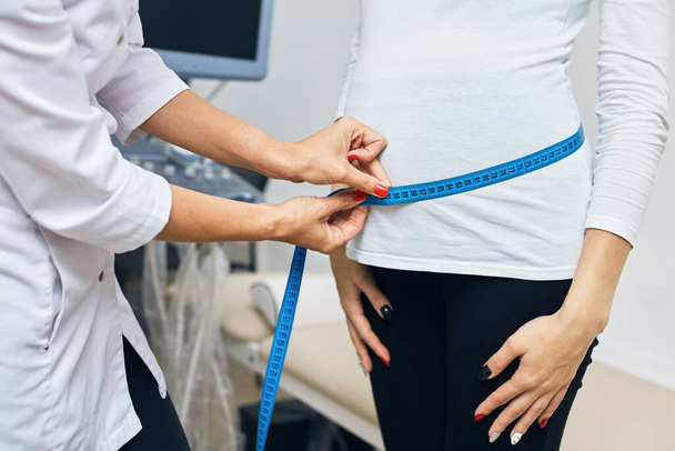 Doctor measuring pregnant girls belly - Fotoğraf, Görsel