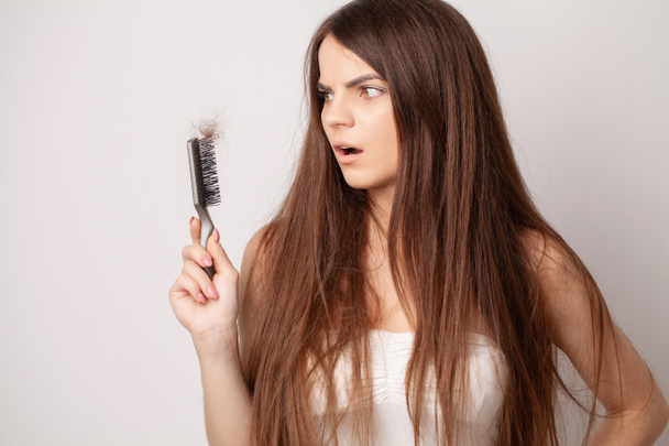 Very upset young woman with comb and problem loss hair. - Photo, Image