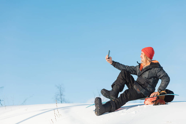 cheerful blond man in winter snowboard clothing sitting - Photo, image