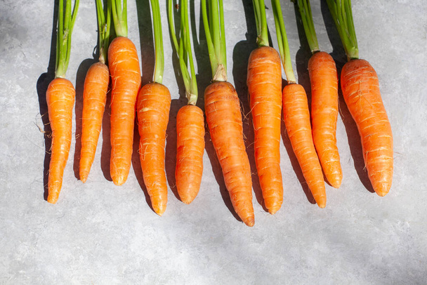 Groupe de carottes vue de dessus, cru avec des tiges et des feuilles sur fond clair. - Photo, image