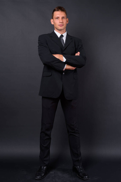 Studio shot of businessman wearing suit against black background - Photo, Image