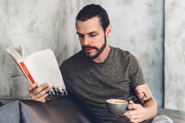 Handsome hipster man relaxing read the paper book work study and looking at page magazine while sitting on chair in cafe and restaurant - 写真・画像