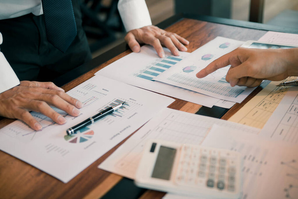 Účetní společnosti společně analyzují graf výdajů na stole v kanceláři. - Fotografie, Obrázek