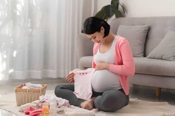 Mãe asiática preparando pouca roupa para o novo bebê quando sentado no chão - Foto, Imagem
