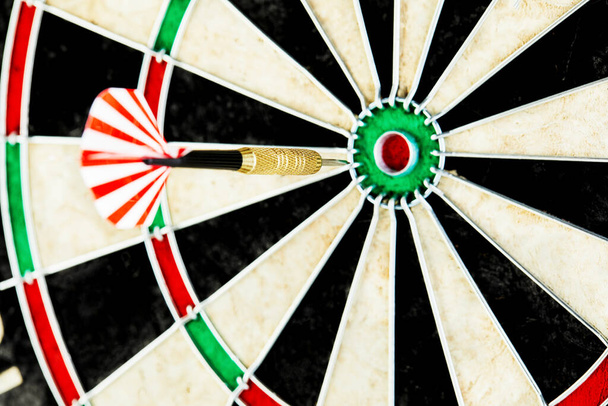 Darts on a black background. 1 dart flies directly to the center of the target. Business center goal concept. - Photo, Image