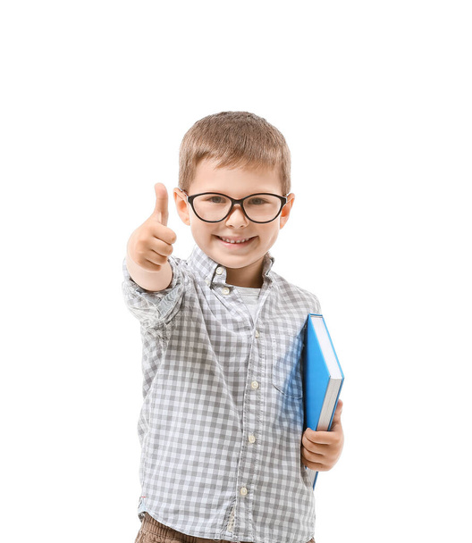 Roztomilý chlapeček s knihou ukazující palec nahoru na bílém pozadí - Fotografie, Obrázek