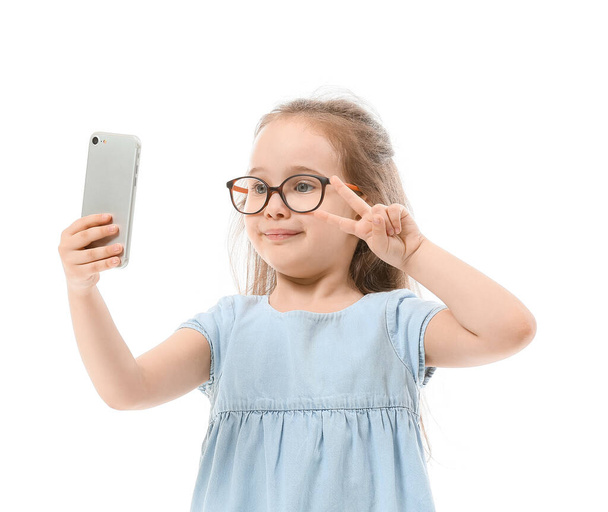 Cute little girl taking selfie on white background - Фото, изображение