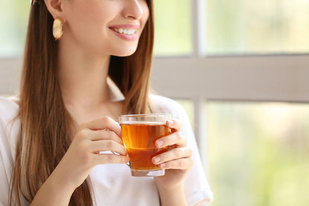 Όμορφη νεαρή γυναίκα πίνει τσάι στο σπίτι - Φωτογραφία, εικόνα