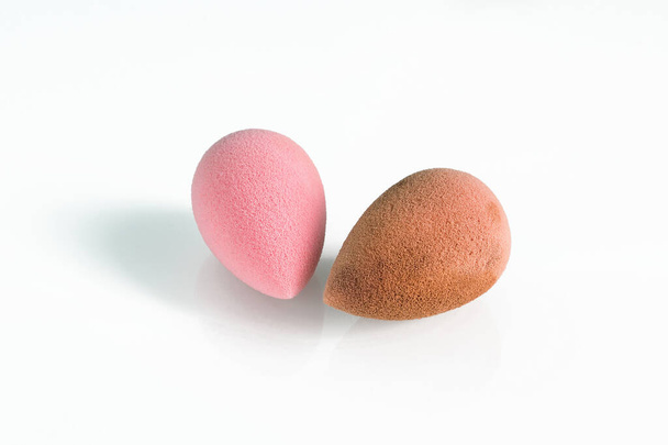 ピンクの美しさ涙形のブレンダー、汚れやきれいな卵の形をしたスポンジは、白い背景に隔離された。化粧用化粧道具. - 写真・画像