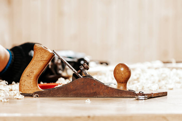 A black   jack plane is on a wooden table, next to a wooden sawdust in the workshop - Photo, Image