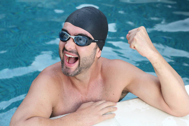 крупным планом портрет красивого молодого человека в плавательных очках и резиновой шляпе в бассейне - Фото, изображение