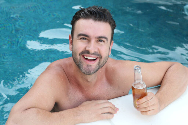 close-up retrato de belo jovem com garrafa de cerveja relaxante na piscina
 - Foto, Imagem