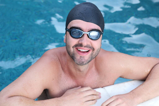 portrait en gros plan de beau jeune homme en lunettes de natation et chapeau en caoutchouc dans la piscine - Photo, image