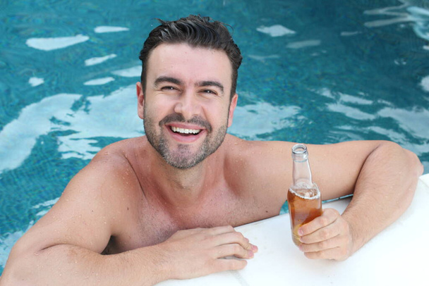 close-up retrato de belo jovem com garrafa de cerveja relaxante na piscina
 - Foto, Imagem