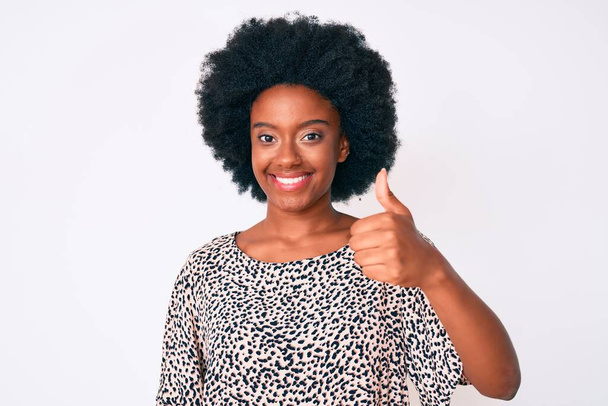 Junge afrikanisch-amerikanische Frau in lässiger Kleidung lächelt glücklich und positiv, Daumen hoch und tut hervorragende und Zustimmung Zeichen  - Foto, Bild