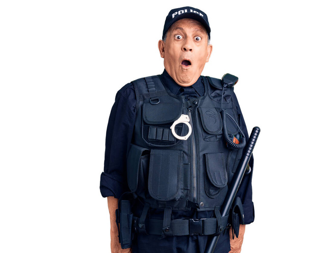 Hombre guapo mayor vistiendo uniforme de policía asustado y sorprendido con la boca abierta para sorpresa, cara de incredulidad  - Foto, imagen